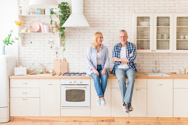 Coppie senior che si siedono sul contatore di cucina