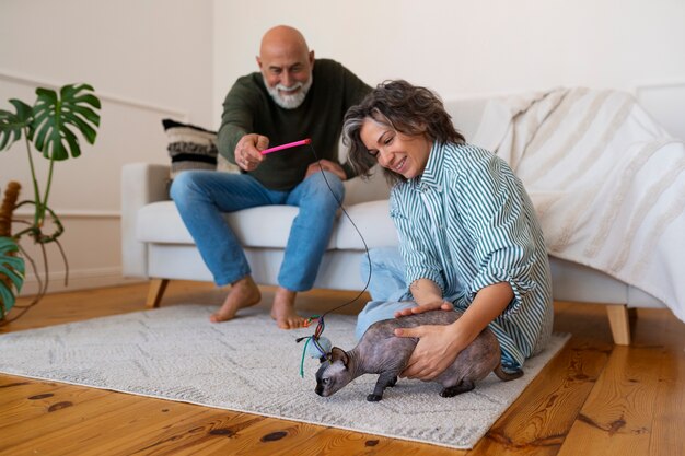 Coppie senior del colpo pieno con il gatto a casa