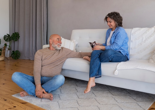 Coppie senior del colpo pieno con il gatto a casa