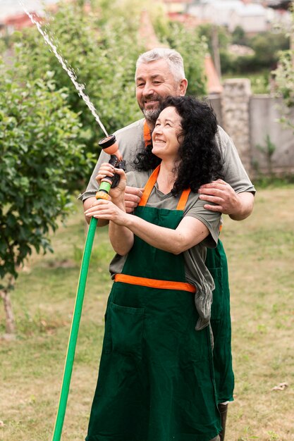 Coppie senior felici con il tubo flessibile dell'acqua