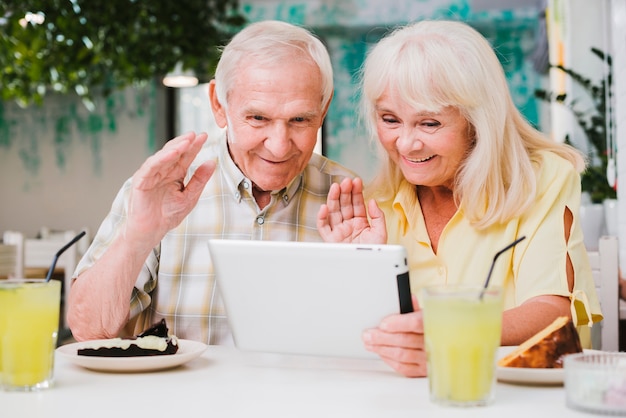 Coppie senior positive in caffè che ha video chiamata sulla compressa