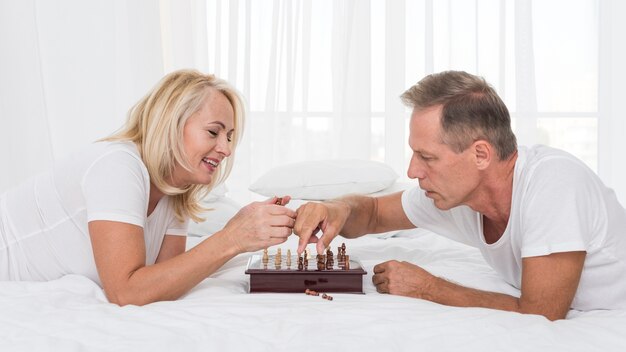 Coppie sorridenti del colpo medio che giocano scacchi