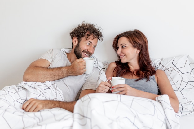 Coppie sveglie che bevono caffè nel letto