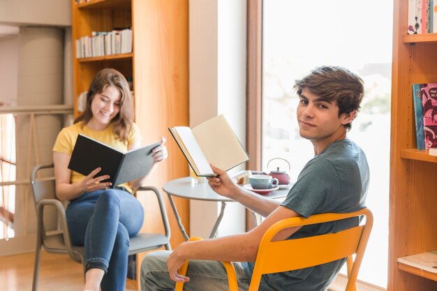 Coppie teenager che leggono nella biblioteca