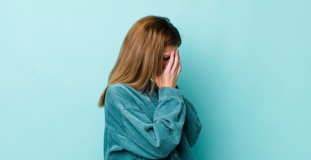 Coprendo gli occhi con le mani con uno sguardo triste e frustrato di disperazione che piange vista laterale