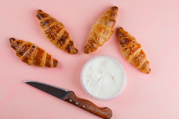 Cornetti con crema di formaggio, coltello piatto disteso su un tavolo rosa