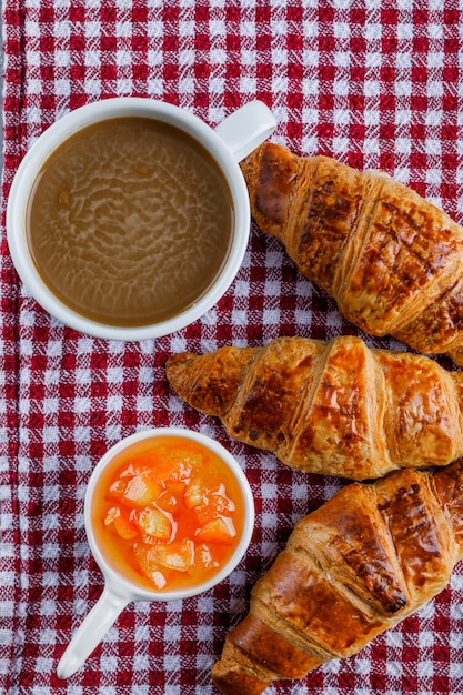 Cornetti con tazza di caffè, salsa su panno da picnic, piatto disteso.