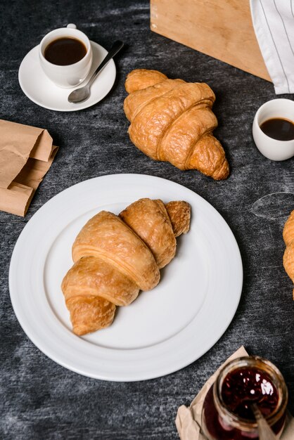 cornetti, pentola con marmellata e tazza di caffè da parte sul tavolo grigio