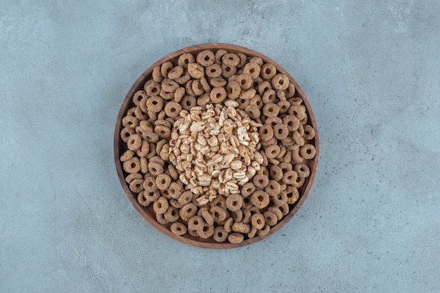 Cornflakes nel piatto di legno, sullo sfondo blu. Foto di alta qualità