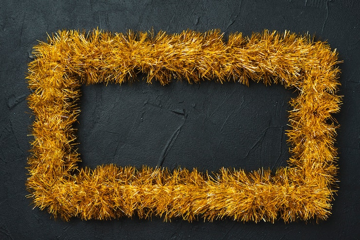 Foto gratuito cornice gialla da tinsel sul tavolo nero