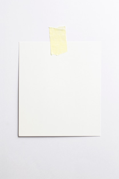 Cornice per foto polaroid in bianco con ombre morbide e nastro adesivo giallo isolato su sfondo di carta bianca