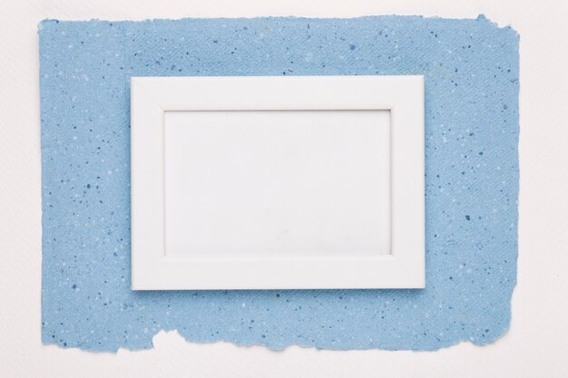 Cornice vuota bianca su carta blu su sfondo bianco