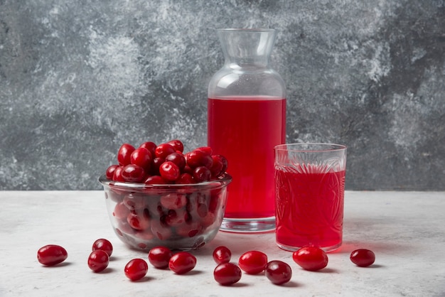 Cornioli con succo nel bicchiere e barattolo.