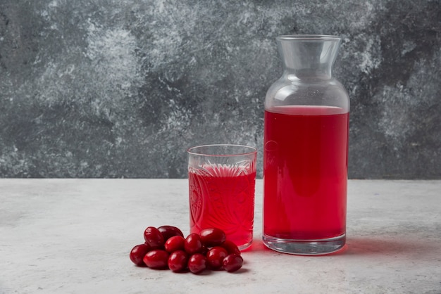 Cornioli con succo nel bicchiere e barattolo.