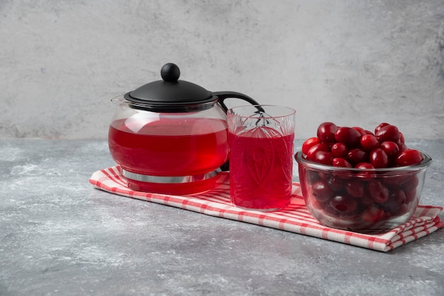 Cornioli e succo rosso in bicchieri e bollitore.