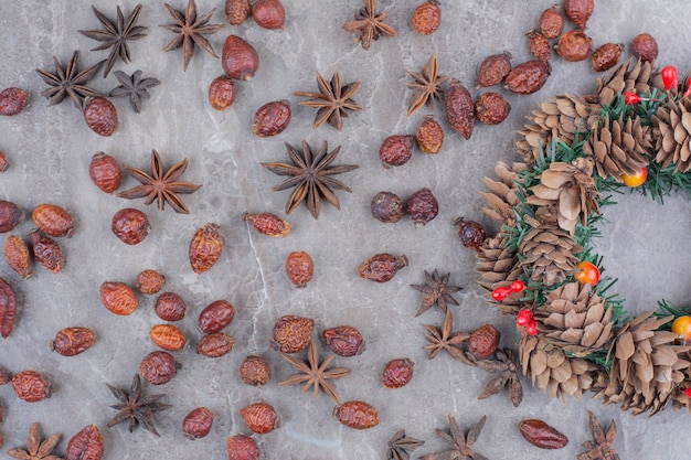 Corona festiva di Natale con pigne nelle quali e anice stellato su fondo di marmo.