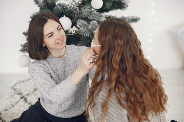 Coronavirus e concetto di Natale. La donna aiuta la sua amica che indossa una maschera.