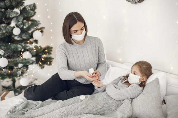 Coronavirus in un bambino. Madre con figlia. Bambino sdraiato in un letto. Donna in una maschera medica.