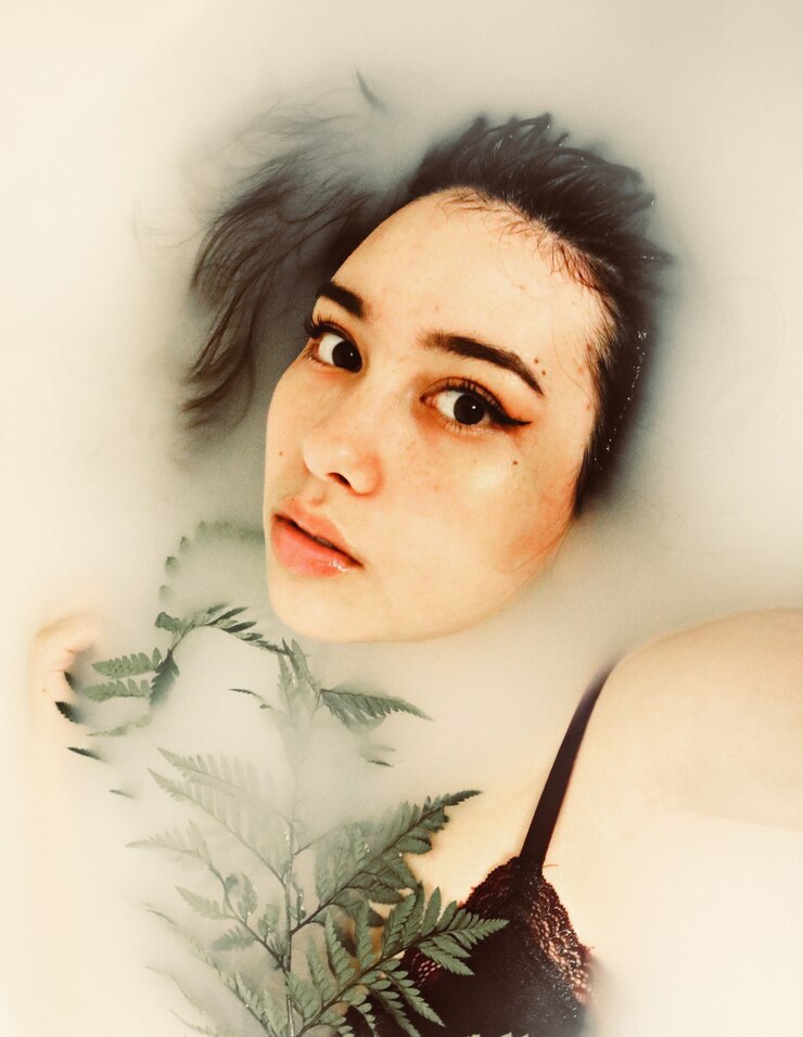 Corpo della donna immerso in acqua che tiene pianta verde