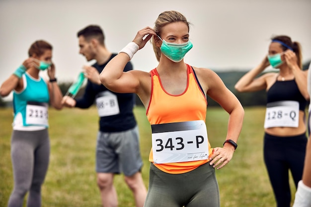 Corridore femminile che indossa una maschera protettiva mentre si prepara per la maratona durante l'epidemia di virus corona