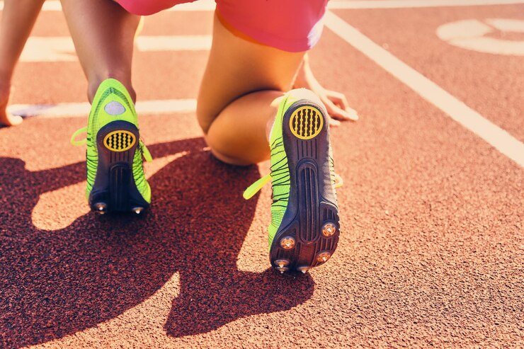 Foto gratuito corridore femminile sportivo biondo in posizione di partenza rapida su uno stadio.