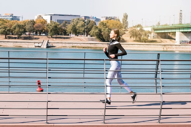 Corridore femminile sportivo di forma fisica sana che corre vicino al lago