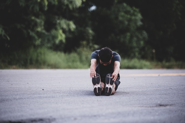 Corridore maschio facendo esercizio di stretching, preparando per allenamento