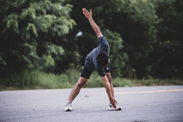 Corridore maschio facendo esercizio di stretching, preparando per allenamento