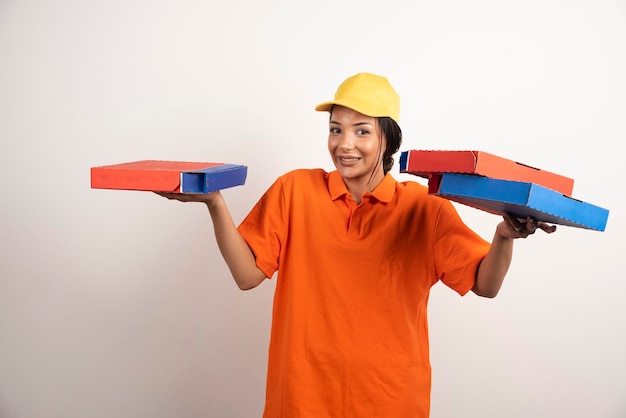 Corriere della donna in uniforme che tiene mazzo di pizze.