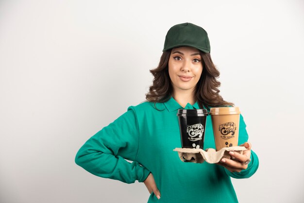 Corriere della donna in uniforme verde che tiene le tazze di caffè.