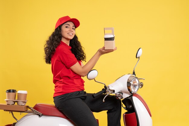 Corriere femminile di vista frontale in bici per la consegna del caffè su fondo giallo uniforme di consegna del servizio lavoratore lavoro donna