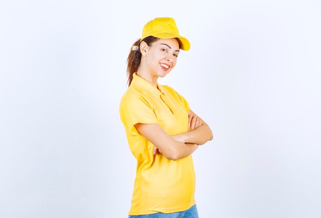 Corriere femminile in uniforme gialla incrociando le braccia e dando pose professionali.