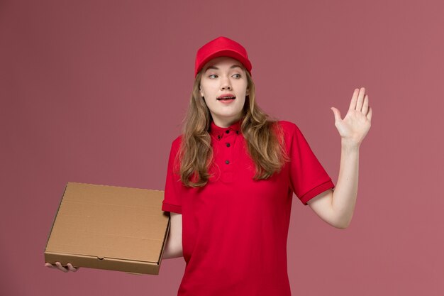 corriere femminile in uniforme rossa che tiene la scatola di cibo per la consegna sul lavoro rosa, uniforme dell'operaio di consegna del servizio