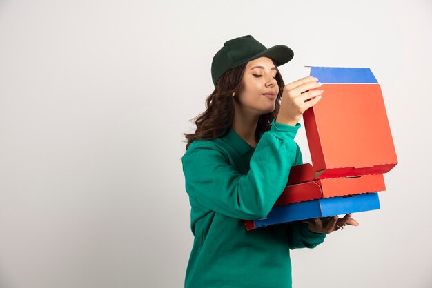 Corriere femminile in uniforme verde che sente l'odore della pizza calda.