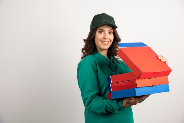 Corriere femminile positivo che tiene la scatola della pizza aperta.