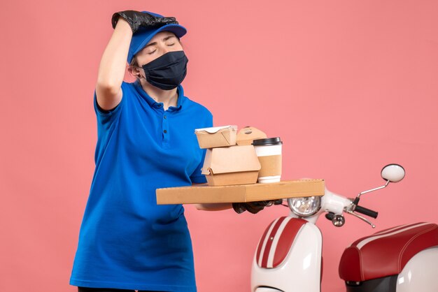 Corriere femminile vista frontale in maschera con consegna caffè e cibo sul rosa