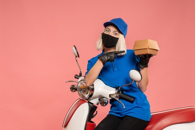 Corriere femminile vista frontale in maschera con poca confezione di cibo sul rosa