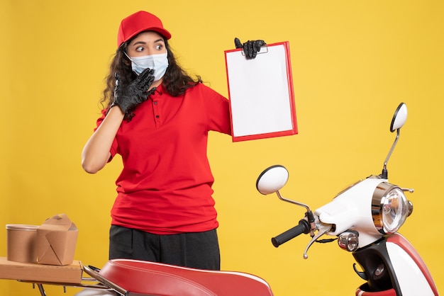 Corriere femminile vista frontale in uniforme rossa con nota di file sulla consegna del pavimento giallo lavoro pandemico lavoratore covid- servizio uniforme