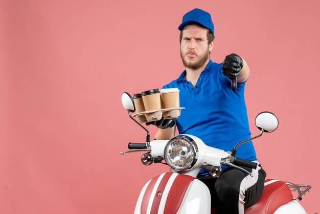 Corriere maschio di vista frontale che si siede sulla bici e che tiene le tazze di caffè sul rosa