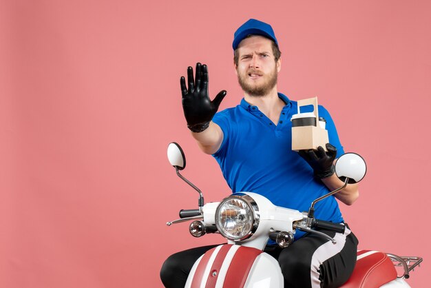 Corriere maschio di vista frontale in uniforme blu che tiene caffè sul lavoro di colore rosa servizio di consegna di fast-food lavoro bici