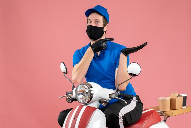 Corriere maschio di vista frontale in uniforme blu e maschera sul lavoro di consegna covid di fast-food della bici del virus del servizio rosa