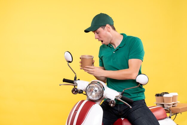 Corriere maschio di vista frontale in uniforme che tiene tazza di caffè su giallo