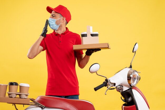 Corriere maschio di vista frontale in uniforme rossa con scatola di cibo e caffè sul servizio di lavoro colore giallo pandemia covid lavoro uniforme virus