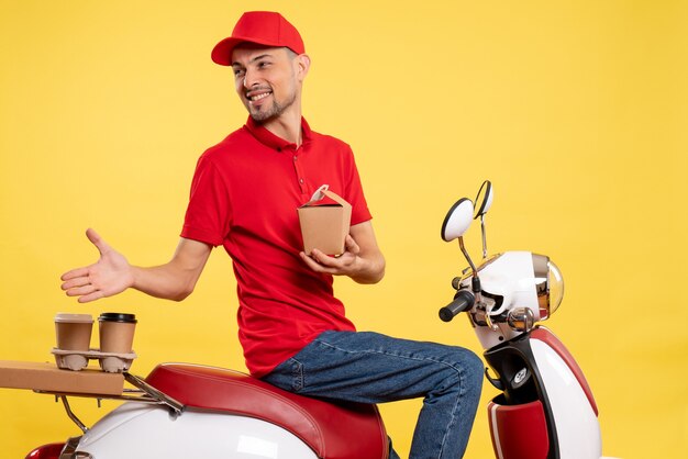 Corriere maschio giovane vista frontale in uniforme rossa con poco cibo di consegna su sfondo giallo