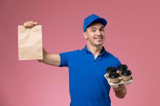 corriere maschio in uniforme blu che tiene il pacchetto di cibo di consegna e caffè in rosa, consegna uniforme del servizio di lavoro lavoratore