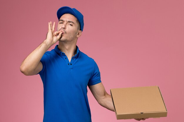 corriere maschio in uniforme blu che tiene la scatola di cibo in posa sulla rosa, consegna del servizio uniforme del lavoratore di lavoro