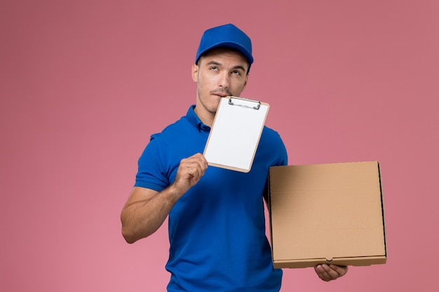 corriere maschio in uniforme blu che tiene la scatola di cibo per la consegna e il blocco note sulla consegna rosa, uniforme del servizio di lavoro lavoratore