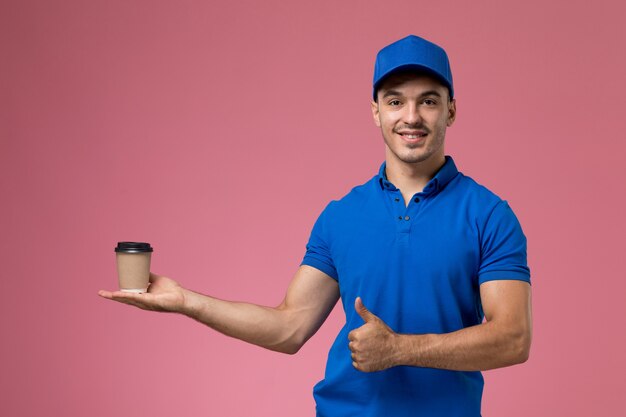 corriere maschio in uniforme blu che tiene la tazza di caffè di consegna e posa sulla consegna di servizio dell'operaio di lavoro rosa e uniforme