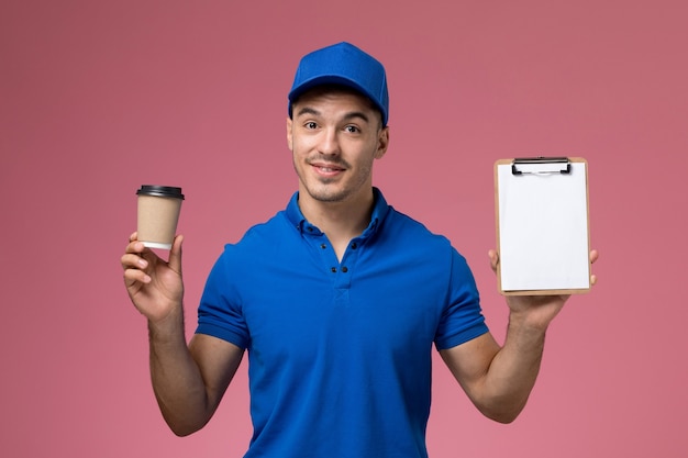 corriere maschio in uniforme blu che tiene tazza di caffè con blocco note sul rosa, consegna del servizio uniforme di lavoro