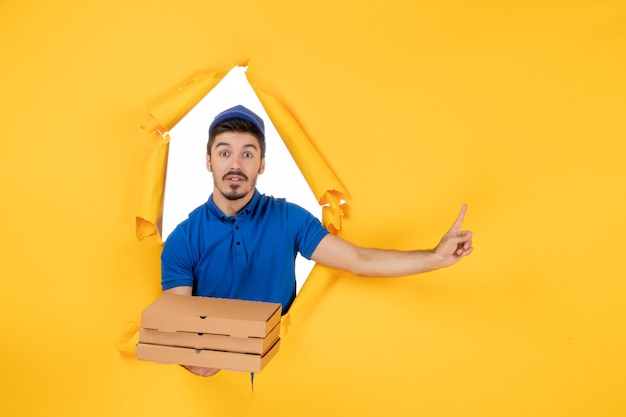 Corriere maschio vista frontale che tiene scatole per pizza su spazio giallo